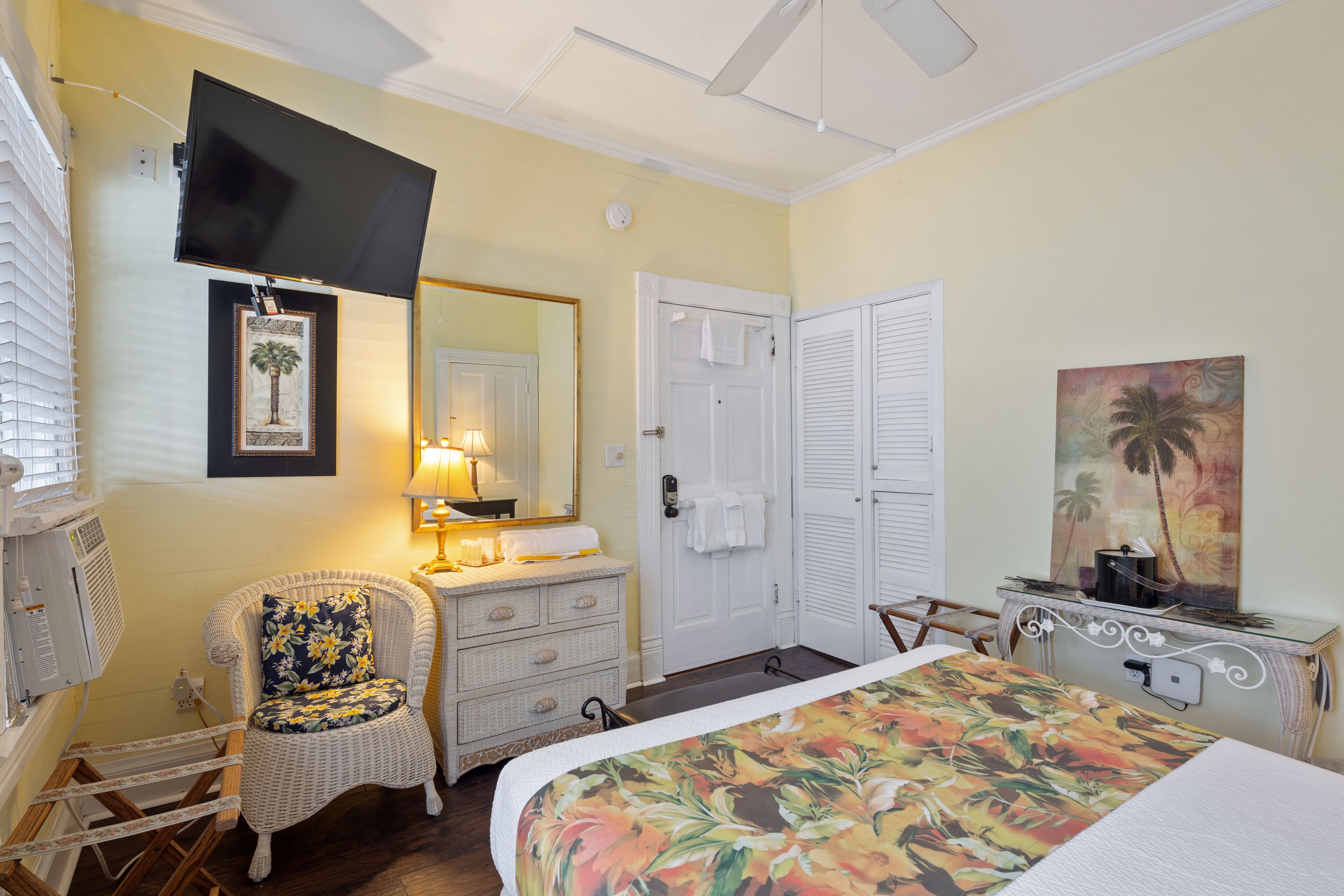 A hotel room with a bed, a chair, a dresser, a television mounted on the wall, and a door with a towel hanging on it.