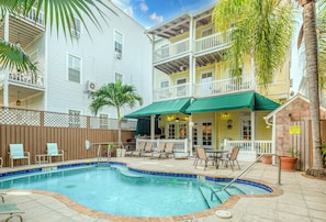 A pool area with lounge chairs and a covered patio. - Curry House (Key West)
