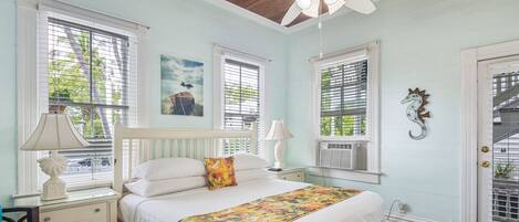 A bedroom with a bed, nightstands, a ceiling fan, and a door with a window.