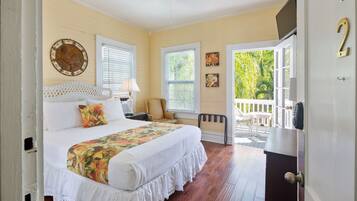 A bedroom with a bed, a nightstand, a chair, and a door leading to a balcony.