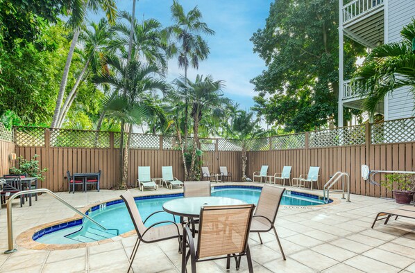 A backyard with a swimming pool, lounge chairs, and a table. - Curry House (Key West)