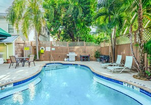 A swimming pool with a wooden deck, lounge chairs, and a barbecue area. - Curry House (Key West)