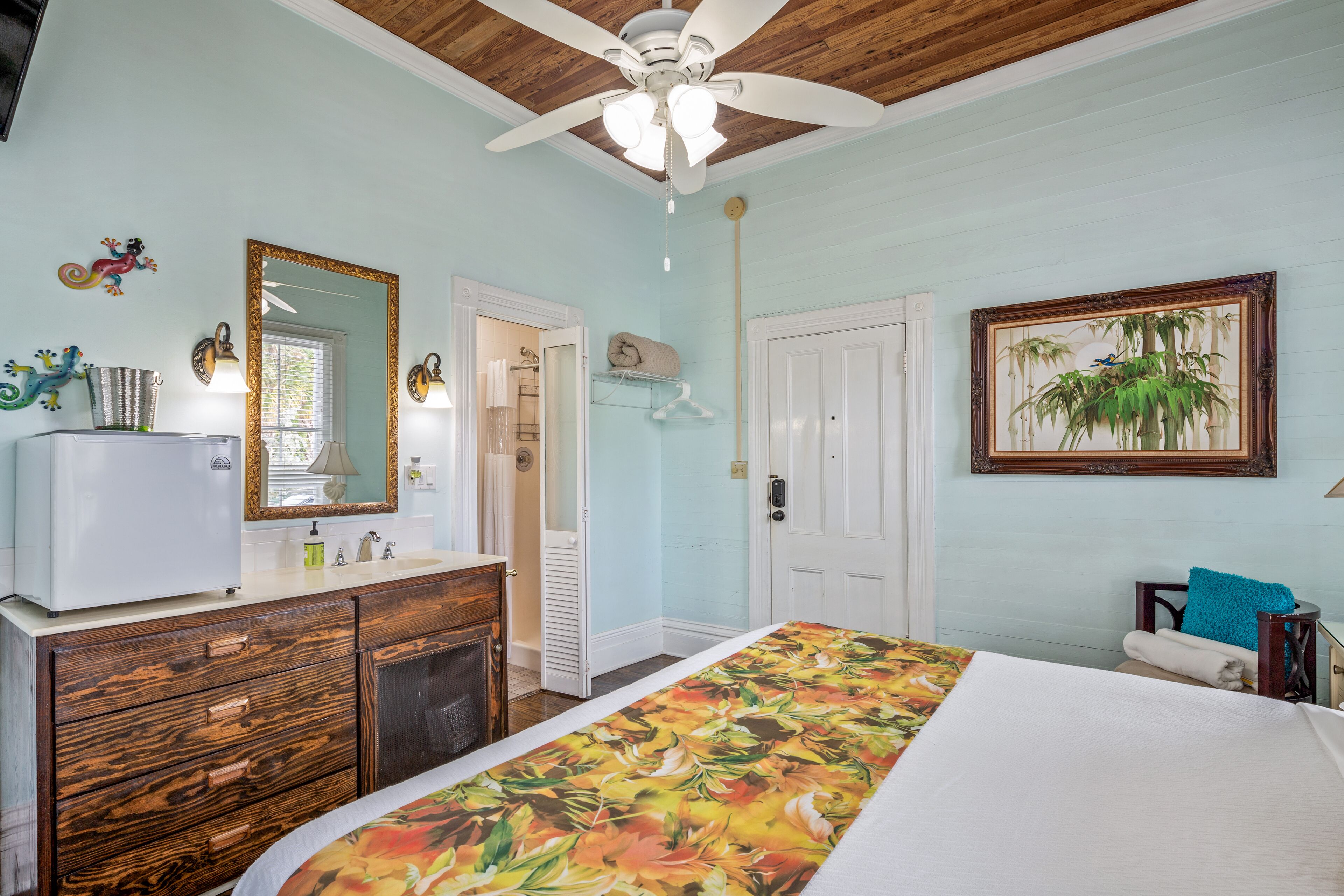 A bedroom with a bed, dresser, vanity, and a ceiling fan.