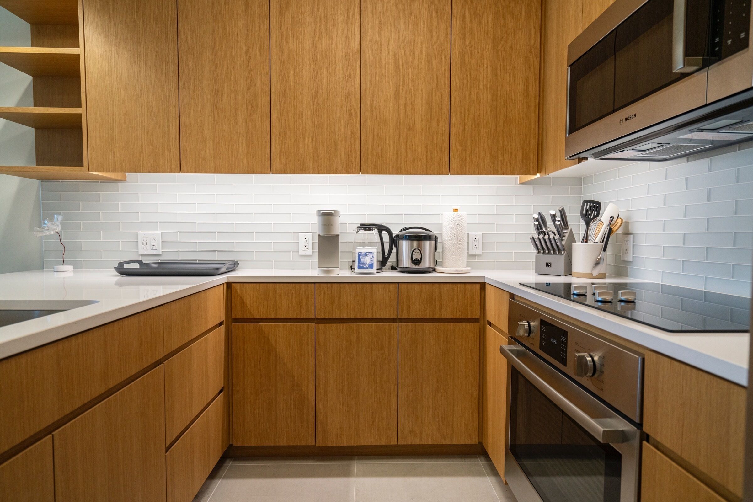 Een moderne keuken met houten kastjes, een roestvrijstalen oven en een magnetron.