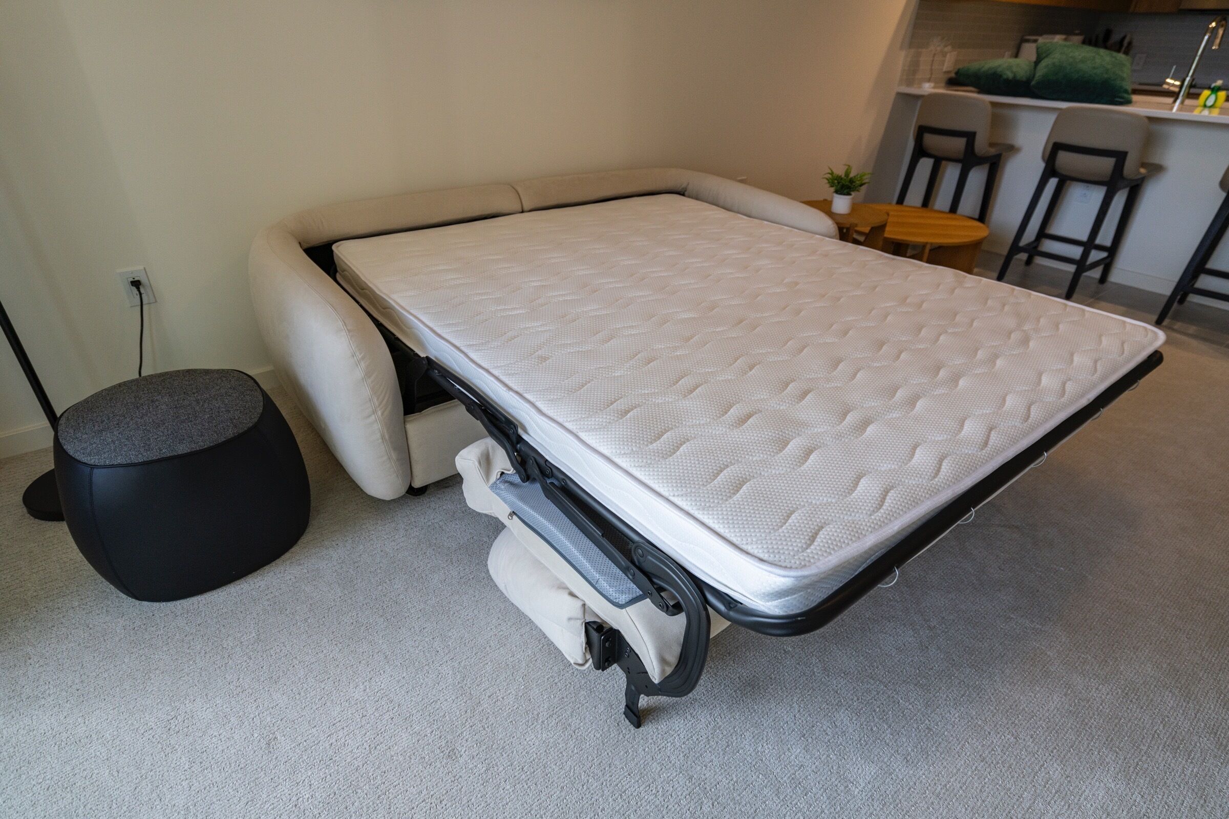 Ein kleines Zimmer mit einem kompakten Bett und einer Küchenzeile im Hintergrund.