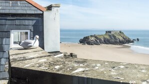 A building with a stone pillar and a seagull on the roof. - The Penthouse - Luxury 1 Bed - Panorama - Tenby (Tenby)