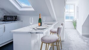 A modern kitchen with a skylight, a bar area with a bottle of champagne, and a view of the sea. - The Penthouse - Luxury 1 Bed - Panorama - Tenby (Tenby)