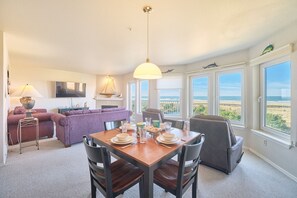 Un comedor con una mesa preparada para cuatro, un sofá y vistas a la playa.