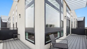 A modern building with large windows and a wooden deck. - Skyline Penthouse | Espadin LoHi (Denver)