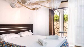 Una habitación de hotel con una cama, una mesita y vistas al verde exterior.