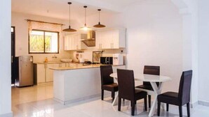 Una cocina moderna con armarios blancos, una isla central e iluminación colgante.