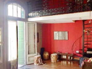 A room with a red wall, a large window, and a balcony with decorative railing. - Artist’s Oasis SanTelmo 2, comfy room for 1-2 people in spacious apt (Buenos Aires)
