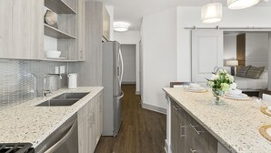 Una cucina moderna con piani di lavoro in granito, elettrodomestici in acciaio inossidabile e mobili in legno.