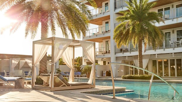 Area piscina con cabana, sedie a sdraio e un edificio a più piani sullo sfondo.