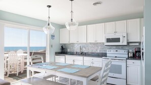A kitchen with white cabinets, a microwave, stove, and a view of the ocean. - 2 Seas the Day West, Oceanfront Duplex in Emerald Isle, NC! (Emerald Isle)
