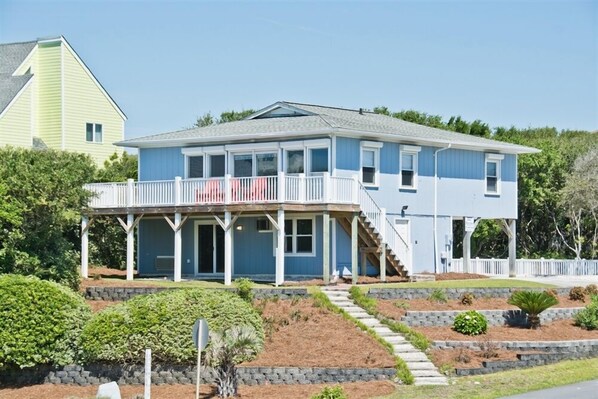 A two-story house with a balcony, a covered porch, and a staircase leading to the second floor. - A Herd Of Turtles, Almost Oceanfront House in Emerald Isle, NC! (Emerald Isle)