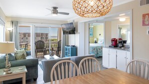 A living room with a dining table, chairs, a sofa, a ceiling fan, and a large woven light fixture. - A Place At The Beach 369, Oceanside Condo in Atlantic Beach, NC! (Atlantic Beach)