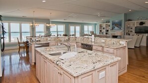 A spacious kitchen with granite countertops, a large island, and a view of the ocean. - A Sandy Ridge, Oceanfront House in Emerald Isle, NC! (Emerald Isle)