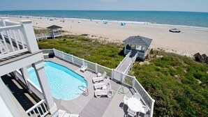 A pool area with a view of the beach, deck chairs, and a gazebo. - A Sandy Ridge, Oceanfront House in Emerald Isle, NC! (Emerald Isle)