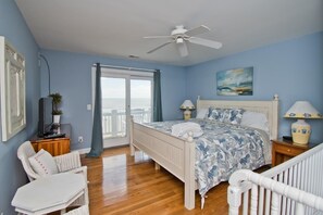 A bedroom with a bed, a ceiling fan, a TV, a chair, and a view of the sea. - A Southern Exposure, Oceanfront House in Emerald Isle, NC! (Emerald Isle)
