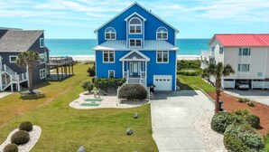 Une maison à deux étages, à la façade bleue, dotée d’un porche et offrant une vue sur l’océan.