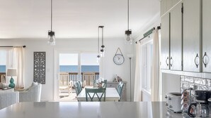 A kitchen with a large island, wooden cabinets, and a view of the beach. - A Wave From it All, Oceanfront Duplex in Emerald Isle, NC! (Emerald Isle)