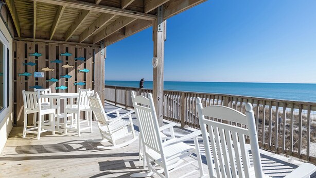 A wooden deck with white chairs and tables, overlooking a beach with a clear blue sky. - A Wave From it All, Oceanfront Duplex in Emerald Isle, NC! (Emerald Isle)