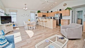 A spacious living area with a dining table, a sofa, and a TV. - Agape West, Oceanfront Duplex in Emerald Isle, NC! (Emerald Isle)