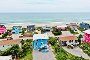 Uma  área residencial costeira com casas de diversas cores, uma praia ao fundo e vista clara para o oceano.
