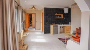 Eine moderne Küche mit schwarzem Rückspritzschutz, einem kleinen Kühlschrank und Holzschränken.