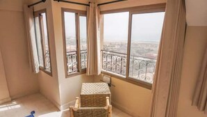 Ein Balkon mit Blick auf eine Stadtlandschaft, ein Korbstuhl und ein kleiner Tisch.
