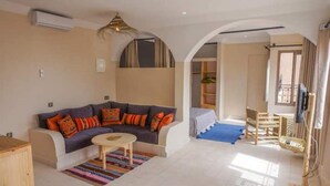 Ein Wohnzimmer mit einer Couch, einem Couchtisch und einem kleinen Teppich. Eine Treppe führt auf eine obere Ebene.