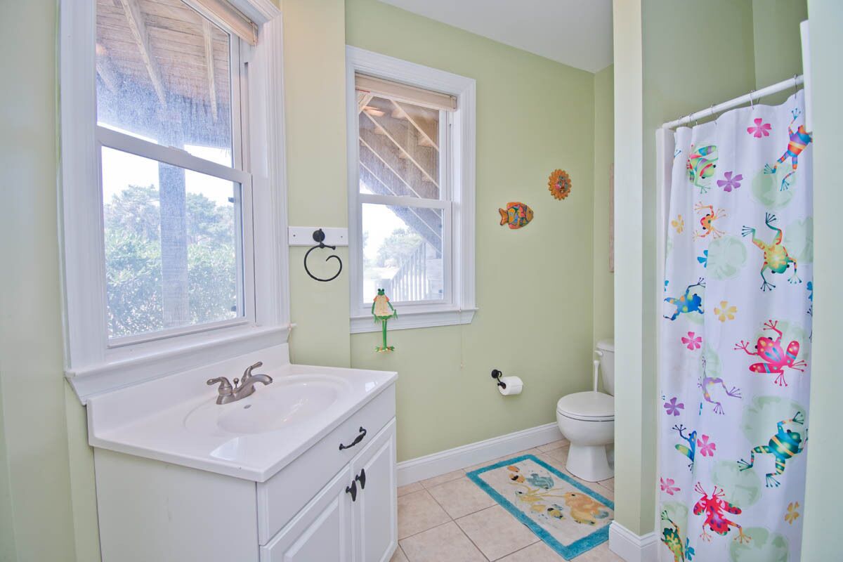 A bathroom with a white sink, a toilet, and a shower curtain with a colorful pattern.