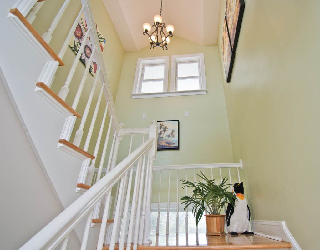 A staircase with white railings and a chandelier.