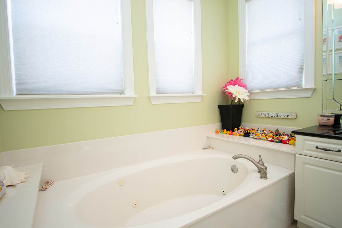 A bathroom with a white bathtub, a shelf with toys, and a sign that reads "Shell Collector".