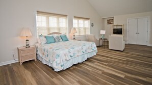 A bedroom with a large bed, two bedside tables, a chair, a TV, and a wardrobe.
