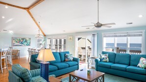 A spacious living room with two teal sofas, a wooden coffee table, and a ceiling fan. - Angel's Dream, Oceanfront House in Emerald Isle, NC! (Emerald Isle)