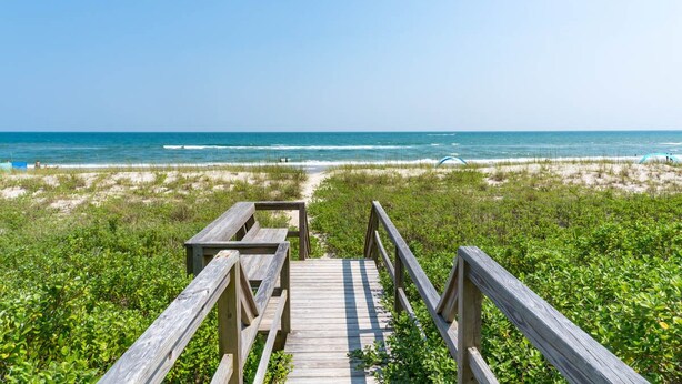A wooden boardwalk leading to the beach with a clear view of the ocean. - Anniversary Waltz East, Oceanfront Duplex in Emerald Isle, NC! (Emerald Isle)