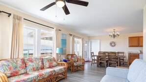 A spacious living area with a sofa, chairs, a dining table, and a ceiling fan. - Anniversary Waltz East, Oceanfront Duplex in Emerald Isle, NC! (Emerald Isle)