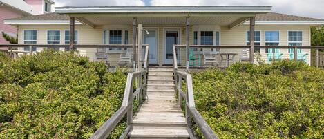 A wooden staircase leading to a building with a porch and multiple windows.