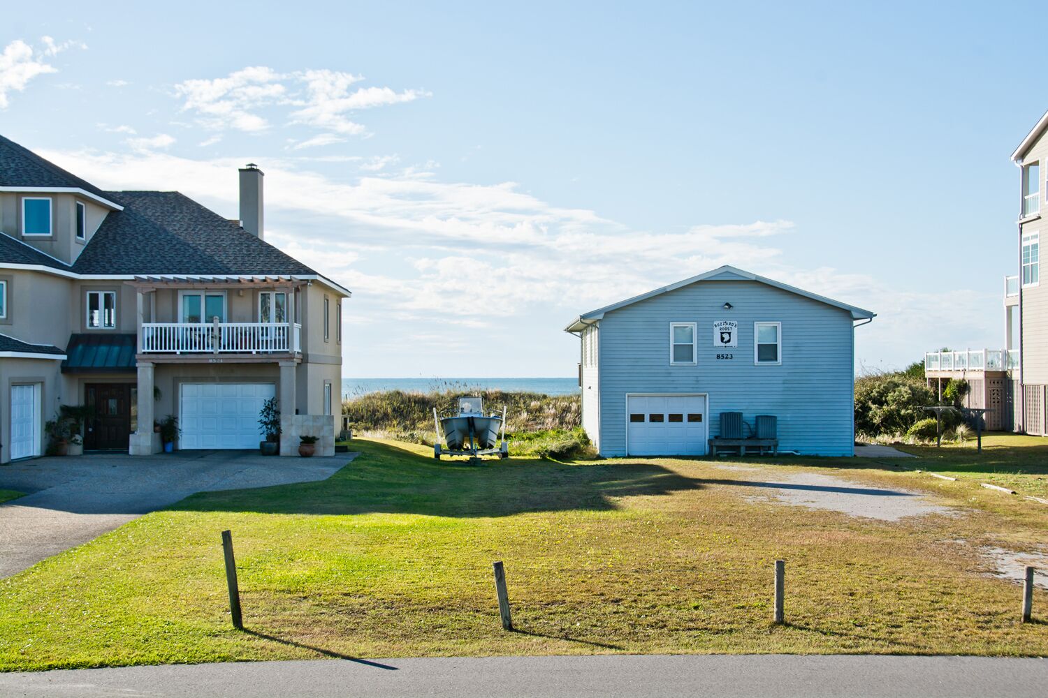 A two-story house with a garage, a small porch, and a view of the beach.