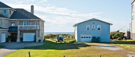 A two-story house with a garage, a small porch, and a view of the beach.