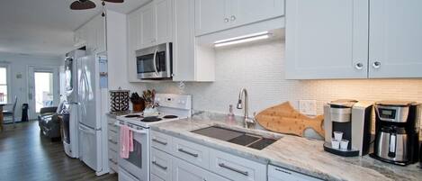A modern kitchen with white cabinets, a microwave, a coffee maker, and a dishwasher.