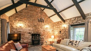 A stone-walled room with a fireplace, leather sofas, and a television.