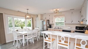 Une cuisine moderne avec des meubles blancs, un îlot central et un coin repas avec des chaises blanches.