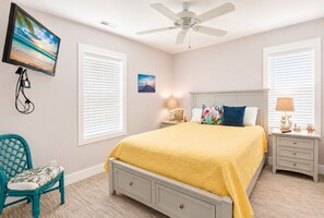 Un dormitorio con cama, ventilador de techo, televisión y una silla.