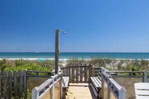 A wooden boardwalk leading to a beach with a clear view of the ocean and a boat in the distance. - Aurora East, Oceanfront Duplex in Emerald Isle, NC! (Emerald Isle)