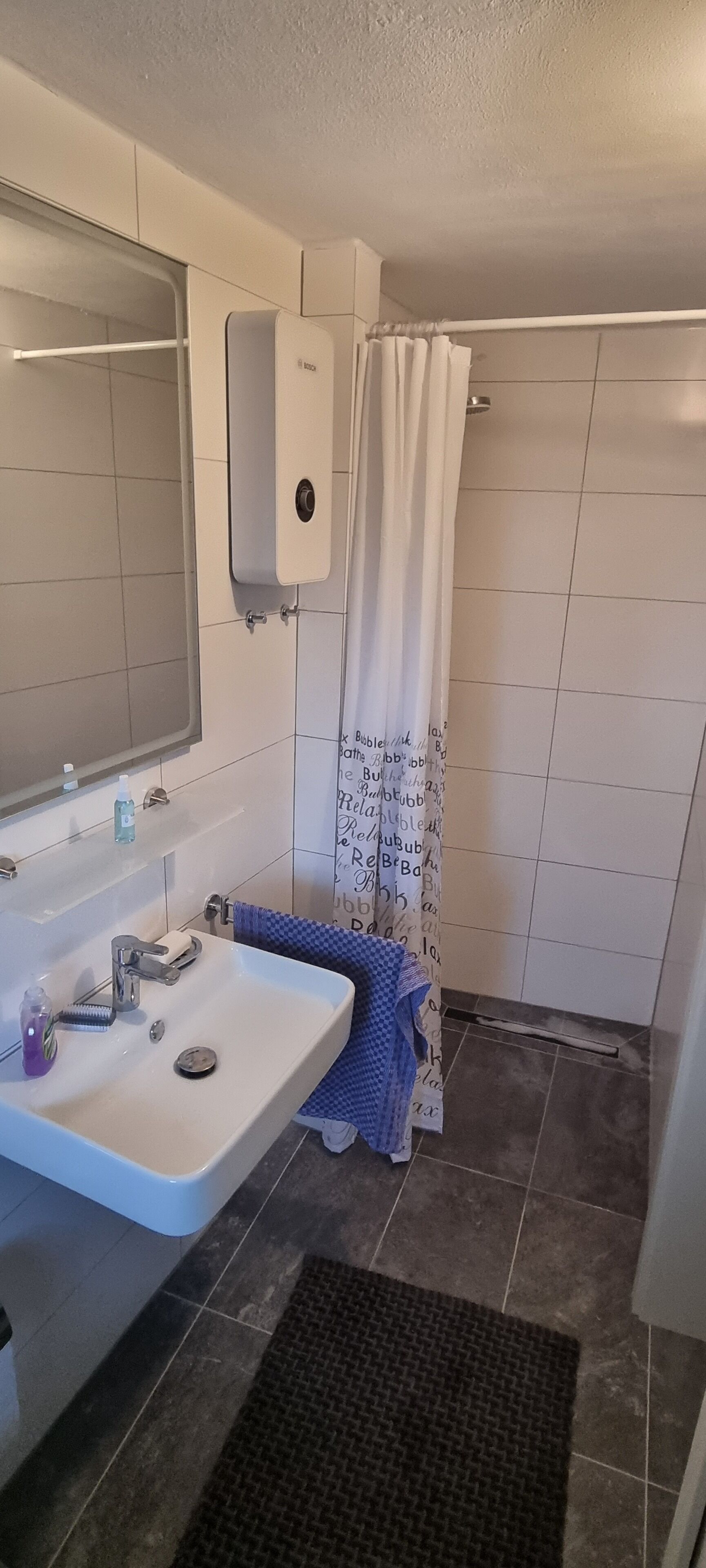 Une salle de bain équipée d’un lavabo, d’un miroir, d’un porte-serviettes et d’un rideau de douche.