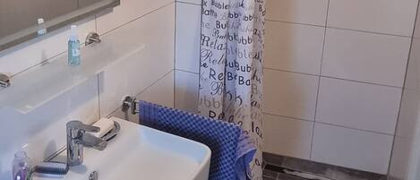 Une salle de bain équipée d’un lavabo, d’un miroir, d’un porte-serviettes et d’un rideau de douche.