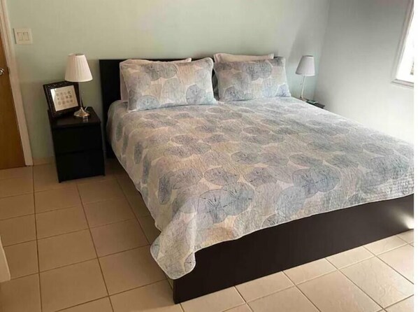 A bedroom with a bed, two nightstands, and a window. - The Turquoise @ Hoopers Bay Beach (Hoopers Bay)